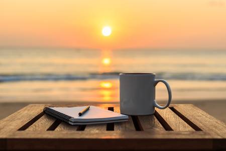 47639945-close-up-coffee-cup-on-wood-table-at-sunset-or-sunrise-beach